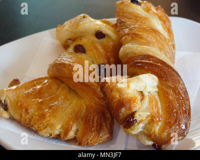 Süßes Gebäck, flockig Croissants mit goldenen Rosinen auf einer weißen Platte Stockfoto