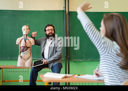 Junge männliche Hispanic Lehrer im Biologieunterricht, digital Tablet und Lehre menschlichen Körper Anatomie, mit künstlichen Körper Modell. Stockfoto