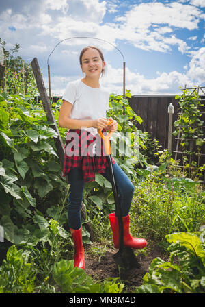 Schönen lächeln Jugendmädchen in Wellington bootas graben die Erde im Garten Stockfoto