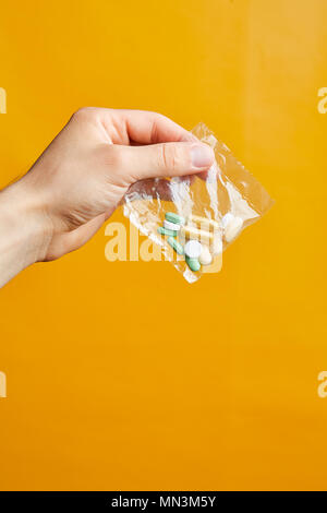 Die Hand eines jungen Mannes mit Pillen. Stapel der Weiße Kapseln und rötliche Tabletten als Medikamente oder Nahrungsergänzungsmittel verwendet Stockfoto