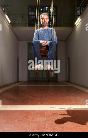 Guy hängenden sitzen auf dem Stuhl, alten industriellen Raum Hintergrund Stockfoto