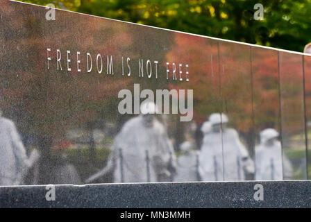 Die Inschrift auf der Mauer an der Korean War Memorial in Washington DC, "Freiheit ist nicht Frei" mit den Überlegungen der Soldat Statuen. Stockfoto