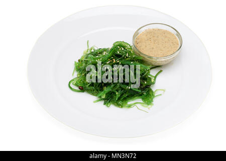 Salat von Sea Kale, Sesam und weiße Sauce auf einer Platte auf weißem Hintergrund Stockfoto
