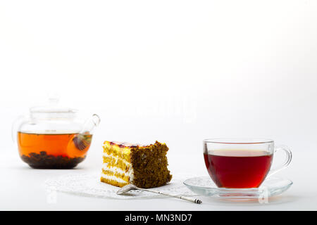 Transparente Teekanne mit Tee, Glas, Becher und Kuchen auf weißem Hintergrund Stockfoto