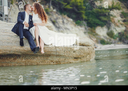 Schönen jungen langhaarigen Braut im weißen Kleid mit ihr junger Ehemann in der Nähe von Fluss Stockfoto