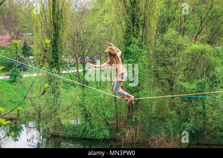 Junge männliche Seiltänzer zu Fuß auf der Slackline in der Luft in einem Park, Straßburg, Frankreich ausgesetzt. Stockfoto