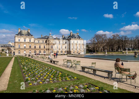 Menschen sitzen im Winter Sonnenschein am achteckigen Pool von Wasser im Jardin du Luxembourg, Paris, Frankreich Stockfoto