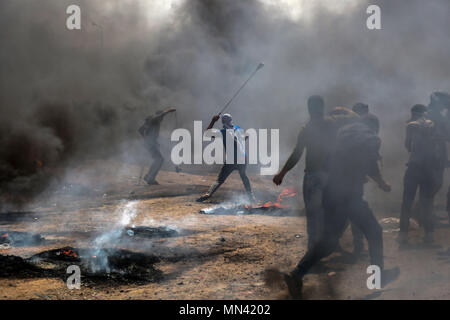 In Gaza. 14 Mai, 2018. Palästinensische Demonstranten mit steinschleudern Steine auf israelische Truppen während der Auseinandersetzungen in Gaza zu schleudern, am 14. Mai 2018. Credit: Stringer/Xinhua/Alamy leben Nachrichten Stockfoto