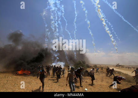 In Gaza. 14 Mai, 2018. Palästinensische Demonstranten laufen Abdeckung von Gas durch israelische Truppen in der Nähe von Grenze feuerte im südlichen Gazastreifen von Khan Younis zerreißen, am 14. Mai 2018. Credit: Khaled Omar/Xinhua/Alamy leben Nachrichten Stockfoto