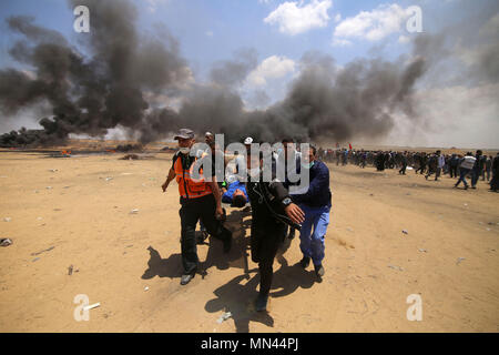 In Gaza. 14 Mai, 2018. Palästinensische Ärzte und die Demonstranten tragen einen verletzten Mann bei Auseinandersetzungen mit israelischen Truppen in der Nähe der Grenze im südlichen Gazastreifen von Khan Younis, am 14. Mai 2018. Credit: Khaled Omar/Xinhua/Alamy leben Nachrichten Stockfoto