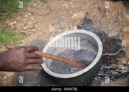 Paidha, Uganda. 5 Mai, 2018. Eine lokale Dorfbewohner gesehen Rösten von Kaffee Bohnen mit Brennholz. Landwirtschaft mehr als 95% des Einkommens für die Dorfbewohner, die sich in den Dörfern in der Nähe der Stadt Paidha im Nordwesten Ugandas nahe der Grenze zur Demokratischen Republik Kongo leben. Aus all den Landwirtschaft Produkte Kaffee machen mehr als 60 % ihres Gesamteinkommens, den aktuellen Preis für Kaffee ist 5000 Schilling (1,30 USD) $ pro kg, während andere Produkte wie Avocados und Labyrinth im Wert sogar noch weniger. Über 90 % der lokalen Familien leben ohne Elektrizität, und Dorfbewohner haben oft nach Carr Stockfoto