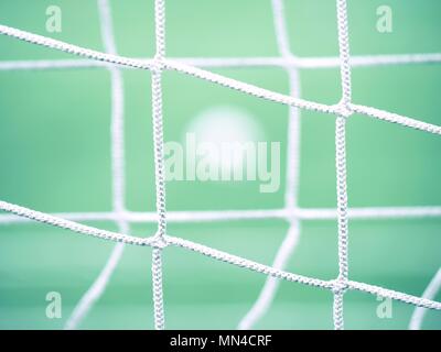Blick durch Fußball Tor net. Fußball auf grünem Gras durch quadratische net gesehen Stockfoto