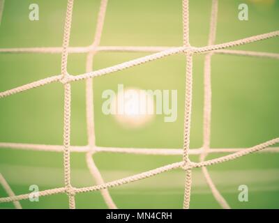Blick durch Fußball Tor net. Fußball auf grünem Gras durch quadratische net gesehen Stockfoto