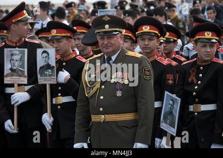 Ein Offizier der Streitkräfte der Pridnestrovianischen Republik Moldawien des halbanerkannten Staates Transnistria steht mit Kadetten des Militärinstituts des Verteidigungsministeriums und hält Fotos von Verwandten, die während einer militärischen Zeremonie anlässlich des Siegestages am 9. im Zweiten Weltkrieg gekämpft haben Mai, der an den Sieg der Sowjetunion über Nazi-Deutschland in Tiraspol erinnert, der Hauptstadt und Verwaltungszentrum der international anerkannten Grenzen Moldawiens, die de facto unter der nicht anerkannten Pridnestrovianischen Republik Moldau steht, die seit 1992 auch Transnistria (PMR) genannt wird. Stockfoto