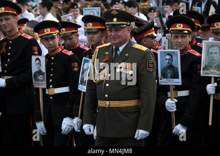 Ein Offizier der Streitkräfte der Pridnestrovianischen Republik Moldawien des halbanerkannten Staates Transnistria steht mit Kadetten des Militärinstituts des Verteidigungsministeriums und hält Fotos von Verwandten, die während einer militärischen Zeremonie anlässlich des Siegestages am 9. im Zweiten Weltkrieg gekämpft haben Mai, der an den Sieg der Sowjetunion über Nazi-Deutschland in Tiraspol erinnert, der Hauptstadt und Verwaltungszentrum der international anerkannten Grenzen Moldawiens, die de facto unter der nicht anerkannten Pridnestrovianischen Republik Moldau steht, die seit 1992 auch Transnistria (PMR) genannt wird. Stockfoto