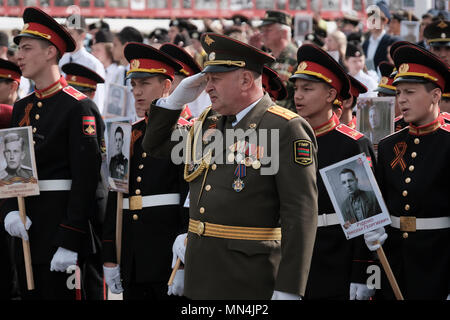 Ein Offizier der Streitkräfte der Pridnestrovianischen Republik Moldawien des halbanerkannten Staates Transnistria grüßt als Kadetten des Militärinstituts des Verteidigungsministeriums halten Fotos von Verwandten, die während einer militärischen Zeremonie anlässlich des Siegestages am 9. im Zweiten Weltkrieg gekämpft haben Mai, der an den Sieg der Sowjetunion über Nazi-Deutschland in Tiraspol erinnert, der Hauptstadt und Verwaltungszentrum der international anerkannten Grenzen Moldawiens, die de facto unter der nicht anerkannten Pridnestrovianischen Republik Moldau steht, die seit 1992 auch Transnistria (PMR) genannt wird. Stockfoto