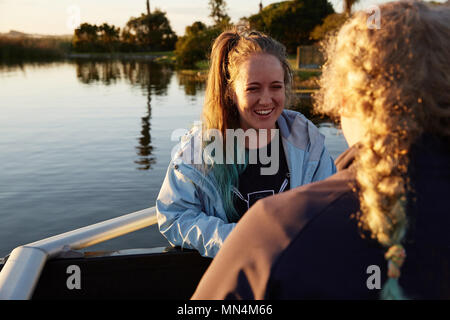 Lächelnd weibliche Ruderer am sonnigen Seeufer Stockfoto