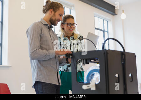 Designer mit Laptop neben dem 3D-Drucker im Büro Stockfoto