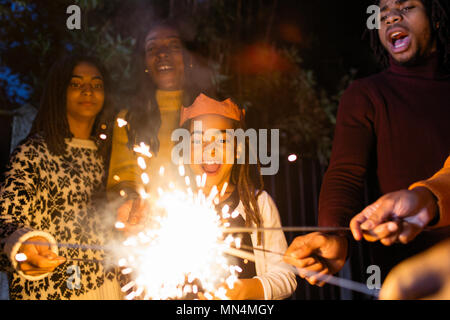 Verspielte Mädchen mit Wunderkerzen feiern mit Familie Stockfoto