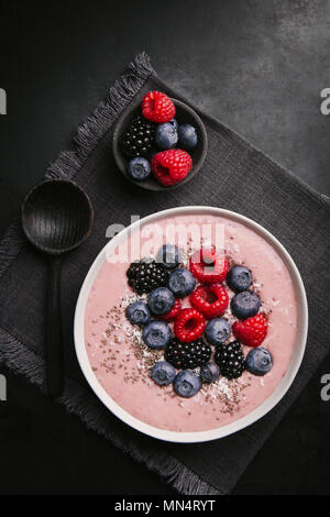 Köstlich leckeren Smoothie Schale mit Beeren auf Platte auf dunklem Hintergrund. Ansicht von oben Stockfoto