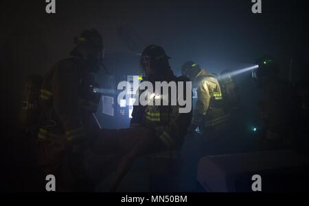 Feuerwehrmänner tragen eine trainingspuppe aus einem Gebäude während eines 27 Special Operations Tiefbau Squadron Training übung für Feuerwehrmänner an Cannon Air Force Base, N.M., 12.08.29., 2017. Feuerwehrleute müssen Kommunikation halten, da sie durch Rauch-gefüllten Gängen navigieren, um schnell Opfer zu finden und zu evakuieren. Stockfoto