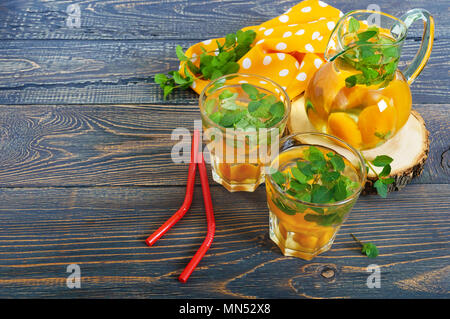 Sommer kalte Getränke. Kompott von Früchten. Köstlich erfrischendes Getränk mit Aprikosen und Minze im Glas auf einen hölzernen Tisch. Stockfoto