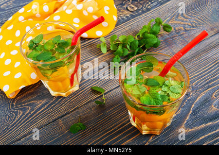 Sommer kalte Getränke. Köstlich erfrischendes Getränk mit Aprikosen und Minze in Gläsern auf einem Holztisch. Kompott von Früchten. Stockfoto