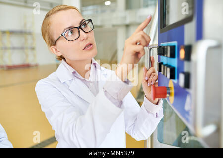 Portraitfotos von sicher ziemlich Arbeiter tragen Brillen und weißen Mantel der CNC-Maschine im geräumigen Produktion Stockfoto