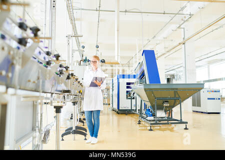 Messe konzentriert - behaarte Arbeiter tragen weiße Fell am Förderband und Controlling Produktion im geräumigen Molkerei Stockfoto