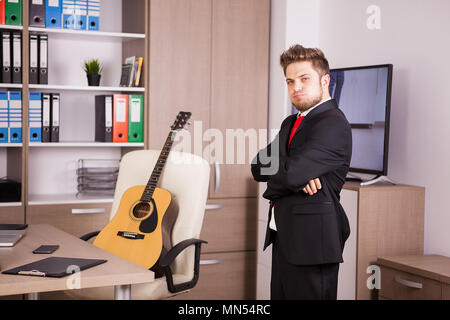 Unternehmer im schwarzen Anzug und roter Krawatte posing Stockfoto