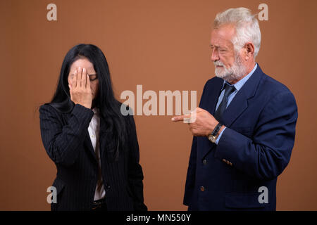 Ausgereifte multi-ethnischen Geschäft Paar gegen braunen Hintergrund Stockfoto