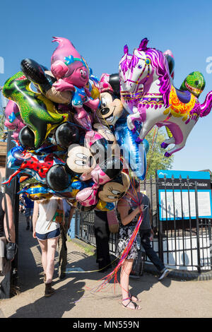 Ein Ballonverkäufer mit einem großen Haufen Heliumballons mit Disney-Figuren an einer Straßenecke in London, England, Großbritannien Stockfoto