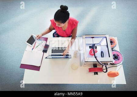 Weibliche Designer bei Laptop neben dem 3D-Drucker Stockfoto