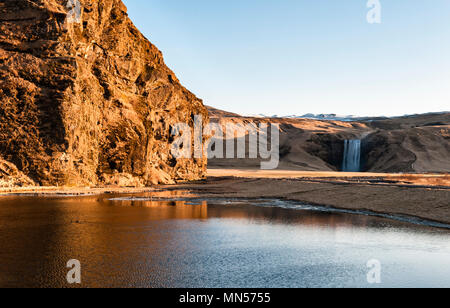 Skógar, South Island. Ein Blick auf den Sonnenaufgang über dem skógá Fluß, nur hinter dem skógafoss Wasserfalls (im Hintergrund) Stockfoto