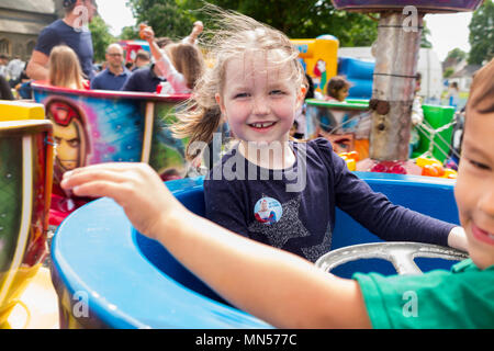 Lächelnde Mädchen im Alter von 6 Jahren alten Fahrten in ein sich drehender Schale Kreisverkehr Fahrt in einem Reisen/Mai Messe besuchen. Sie ist Model Released obwohl andere Menschen nicht freigegeben sind. UK. Stockfoto