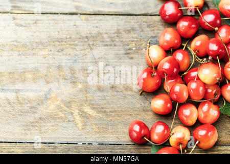 Nahaufnahme von Haufen von reifen Kirschen mit Stängeln und Blättern. Große Sammlung von frischen roten Kirschen. Reife Kirschen Hintergrund. Stockfoto