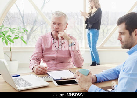 Schuß von Business Team zusammen arbeiten im Büro. Senior Executive Geschäftsmann und Junge am Schreibtisch vor dem Laptop sitzen Assistent und c Stockfoto