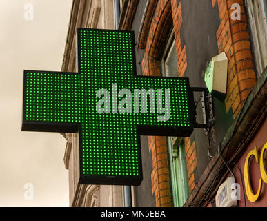 Helle grüne Kreuz Werbung eine Apotheke unten. Stockfoto