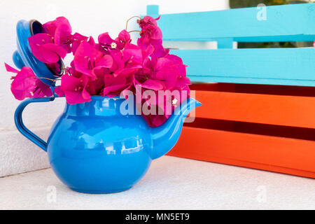 Schöne frische rote Bougainvillea in einem dekorativen Kaffee Topf verwendet als Blumentopf neben bunten Holzkisten Stockfoto