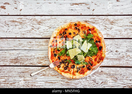 Top down Sicht auf eine leckere Pizza mit Parmesan, Rakete, und Olivenöl Belag auf einem weißen rustikalen vintage Holztisch mit kopieren. Stockfoto