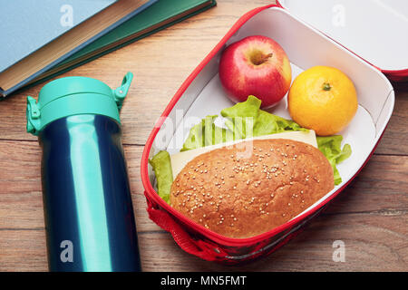 Gesunde Brotdose mit Vollkornbrot Sandwich, frisches Obst und Wasser Flasche auf einem hölzernen Schreibtisch. Konzept der Schule Mittagspause. Stockfoto