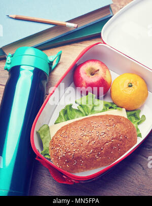 Gesunde Brotdose mit Vollkornbrot Sandwich, frisches Obst und Wasser Flasche auf einem hölzernen Schreibtisch. Konzept der Schule Mittagspause. Stockfoto