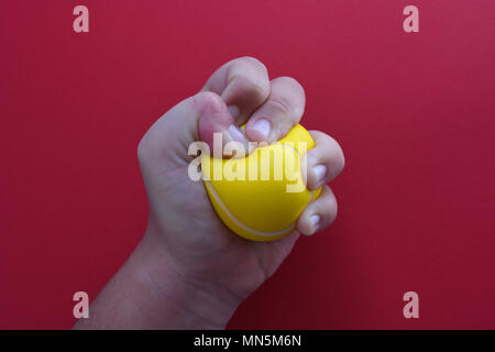 Frau quetschen ein Stress Ball, Nahaufnahme, auf einen einfachen roten Hintergrund mit kopieren. Stockfoto