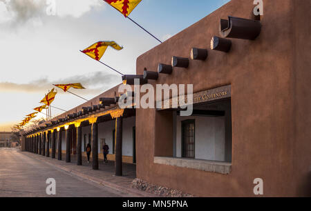 Flaggen über dem Palast der Gouverneure, Santa Fe Plaza, Landeshauptstadt, New York bei Sonnenuntergang auf einem Frühlingsabend fliegen. Historische adobe Struktur. Stockfoto