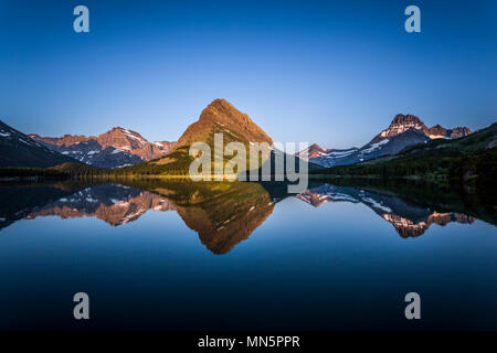 Swiftcurrent Lake und Reflexionen von Grinnel Point und Mount Henkel bei Sonnenaufgang im Glacier National Park, Montana, USA. Stockfoto