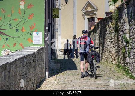 Istrien, Kroatien, April 2018 - Radfahrer Fahrrad drücken Sie die engen gepflasterten Straße in der antiken Stadt Motovun Stockfoto