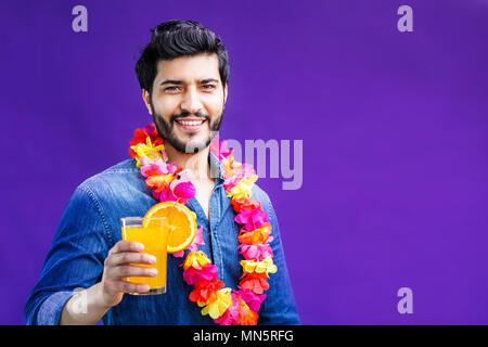 Bärtiger Mann in Lei am Hals gekleidet, hält orange Drink auf lila Hintergrund, Ferienhäuser Konzept, isolierte Studio shot Stockfoto