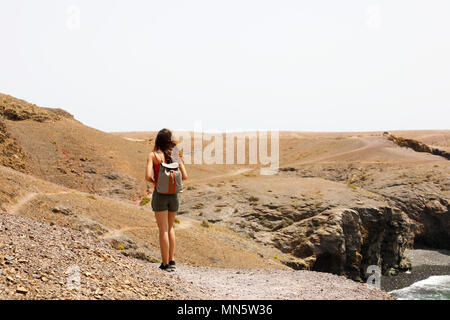 Wandern weiblichen Wandern auf Lanzarote Martian wüstenhaft Landschaft. Zurück Blick auf die junge Frau zu erkunden Vulkaninsel Lanzarote, Kanarische Inseln. Stockfoto