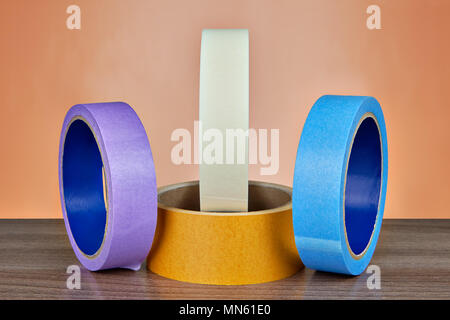 Vier Rollen mit Multi farbigem Klebeband auf orangem Hintergrund. Stockfoto