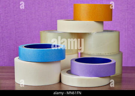 Bürobedarf, Schreibwaren und Papier transparent Klebeband Abdeckband liegt auf Tabelle auf lila Hintergrund. Stockfoto